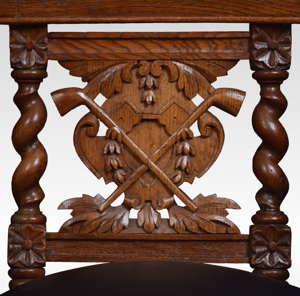 A carved oak side chair with barley twist supports, dark leather padded top rail and seat, and a central coat of arms motif on the backrest. View VII