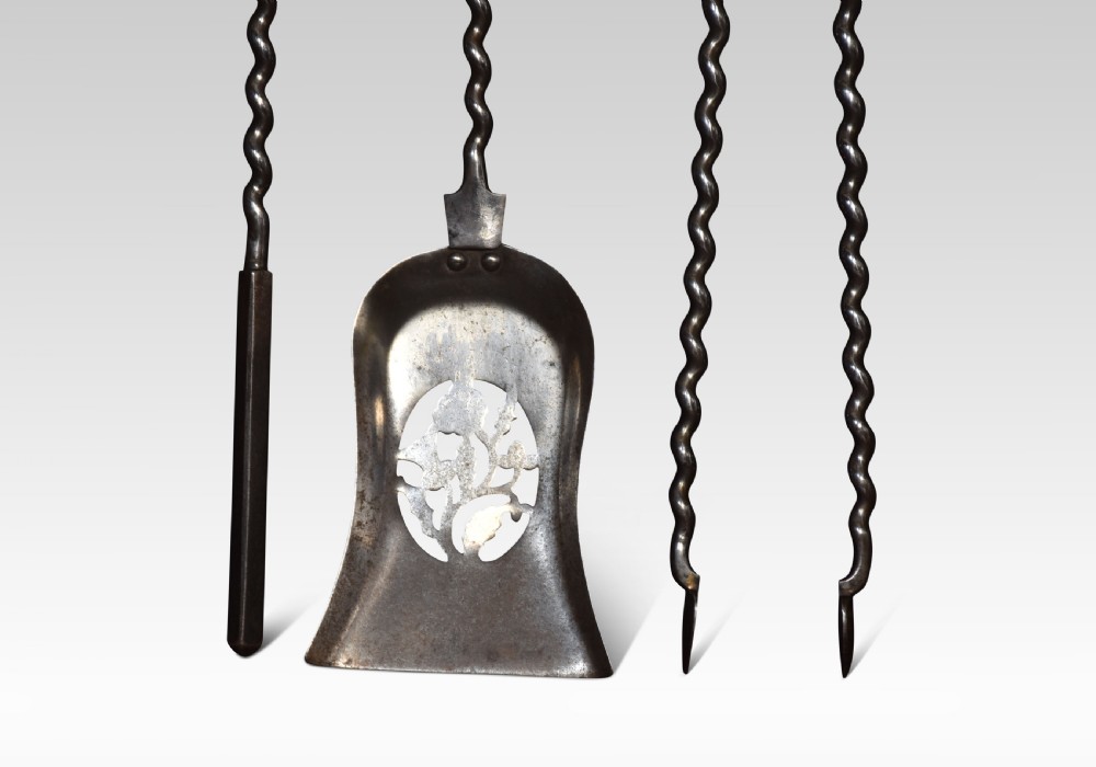 A three-piece set of polished steel fireplace tools comprising a poker, shovel, and tongs with barley twist shafts and turned handles. View III