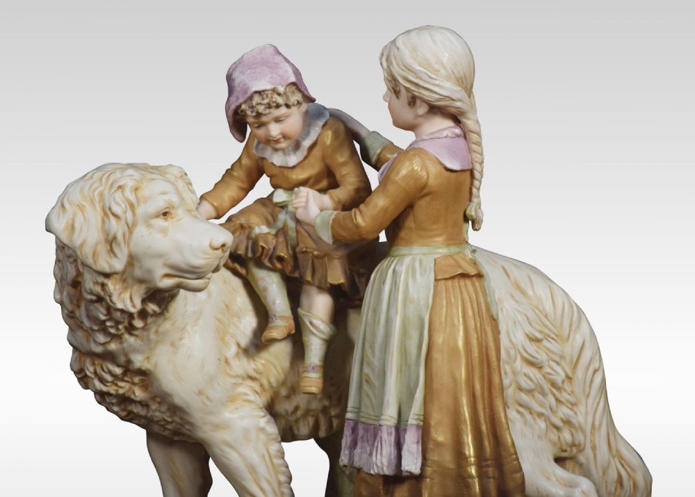 A Royal Dux porcelain figural group depicting two children interactively seated upon and standing beside a large long-haired dog. View III