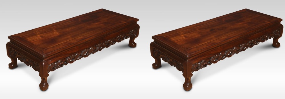 A pair of rectangular low Chinese hardwood coffee tables featuring detailed openwork carved aprons and short cabriole legs.