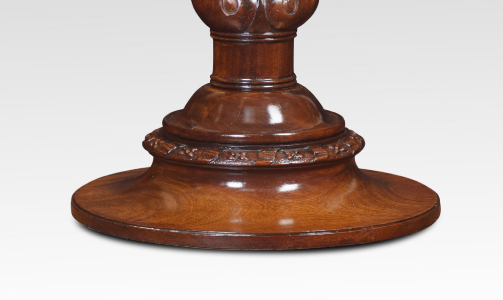A circular mahogany dressing table mirror featuring a carved wooden frame mounted on a central sculpted pedestal base with brass side adjustment knobs. View VI