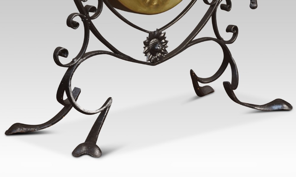 An Art Nouveau freestanding brass dinner gong suspended inside an ornamental dark metal scrollwork frame with an attached mallet striker. View III