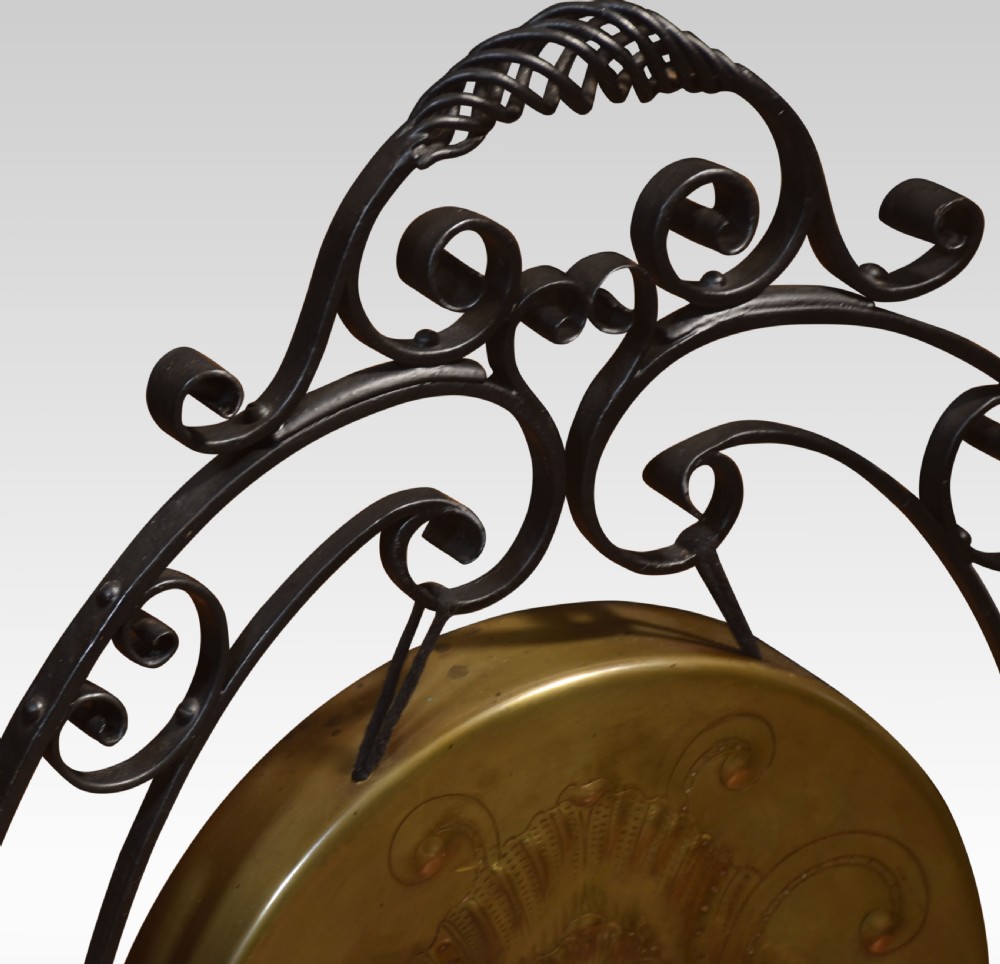 An Art Nouveau freestanding brass dinner gong suspended inside an ornamental dark metal scrollwork frame with an attached mallet striker. View VI
