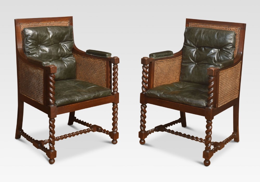 A pair of dark oak bergere library armchairs featuring barley twist legs, woven cane side panels, and deep-tufted dark green leather cushions. View VIII