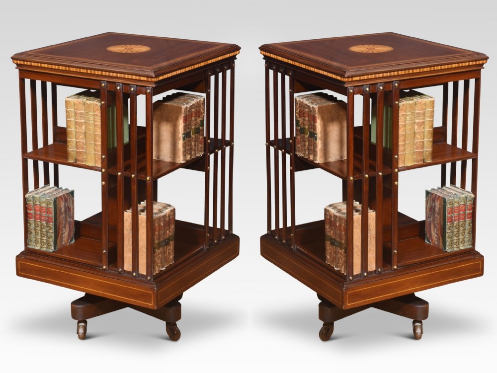 A pair of Edwardian inlaid mahogany revolving bookcases featuring square tops with satinwood crossbanding, vertical slat sides, and rotating bases on castors. View VIII