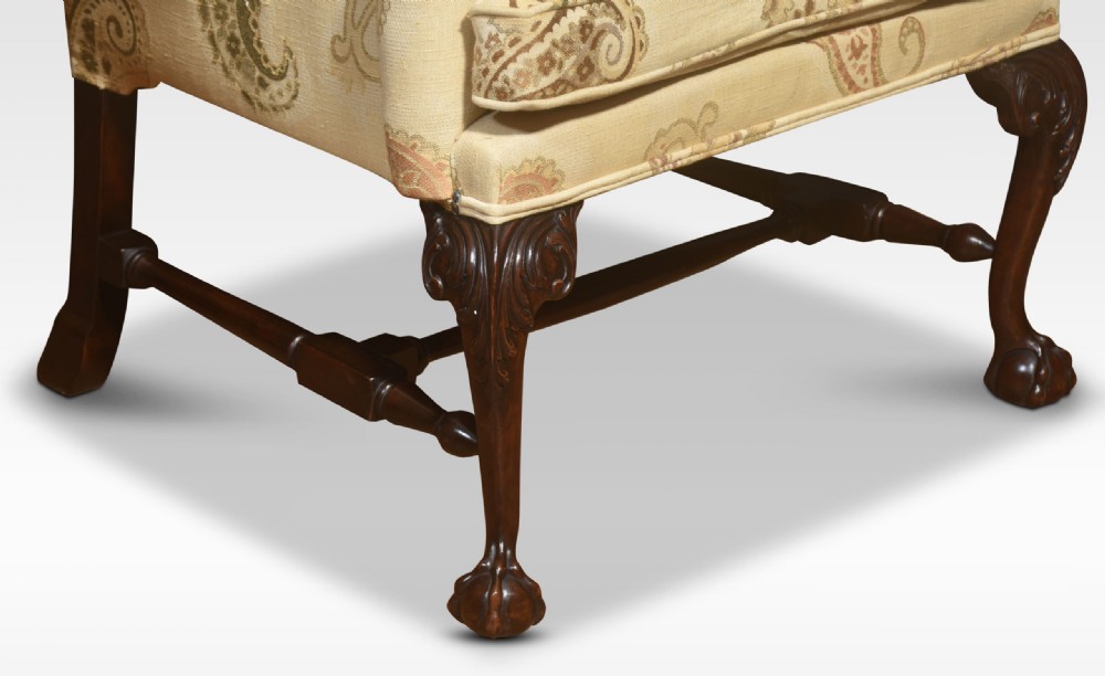 A George II style wing back armchair with pale yellow paisley fabric upholstery, brass studding, and carved mahogany cabriole legs featuring claw and ball feet. View III