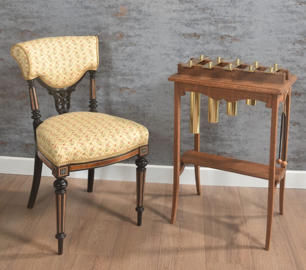 An antique oak glockenspiel stand featuring brass tone bars mounted on top, suspended tubular brass resonators underneath, and two mallets hanging at the side. View II