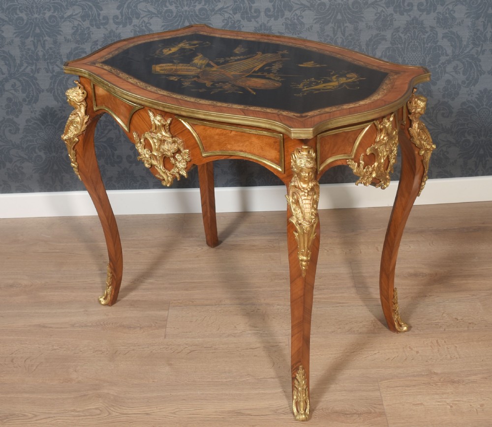 A French Louis XV style walnut centre table featuring cabriole legs, ornate gilt bronze mounts, and an ebonised top decorated with musical instrument marquetry.