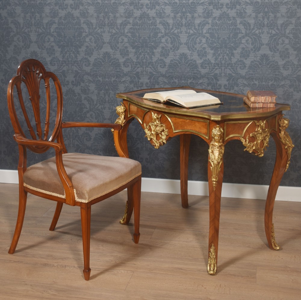 A French Louis XV style walnut centre table featuring cabriole legs, ornate gilt bronze mounts, and an ebonised top decorated with musical instrument marquetry. View II