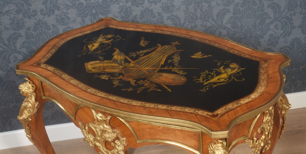 A French Louis XV style walnut centre table featuring cabriole legs, ornate gilt bronze mounts, and an ebonised top decorated with musical instrument marquetry. View III