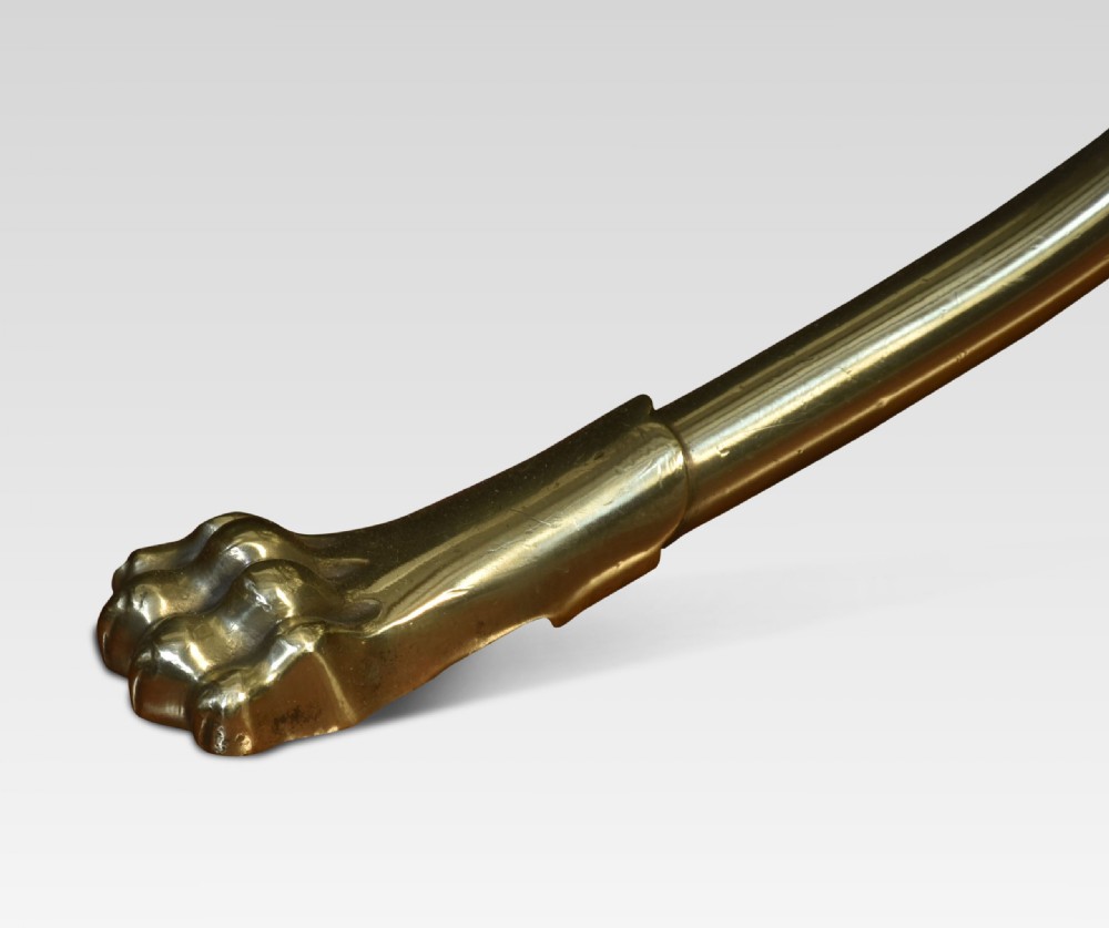 A freestanding brass magazine rack with slatted dividers, decorative side scrollwork, a looped central carrying handle, and four curved legs ending in claw feet. View III