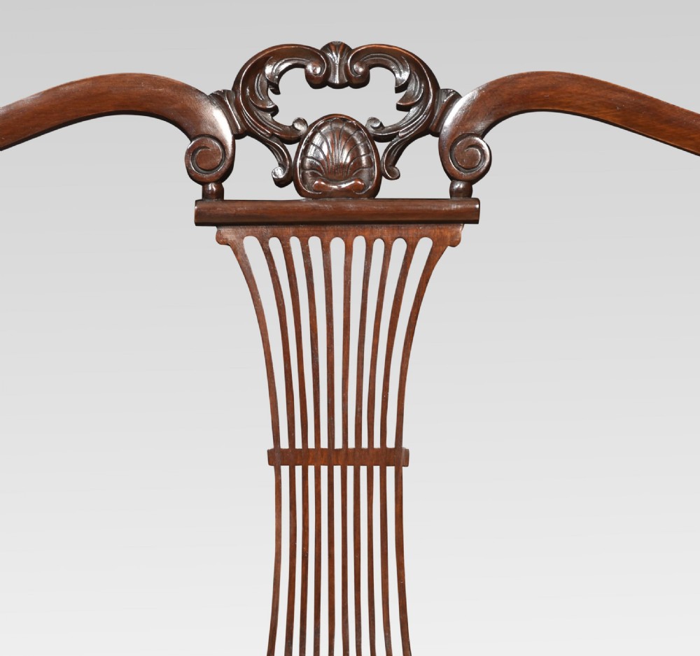 An antique carved mahogany settee featuring a triple fluted splat backrest, sweeping armrests, and a light beige upholstered seat. View V