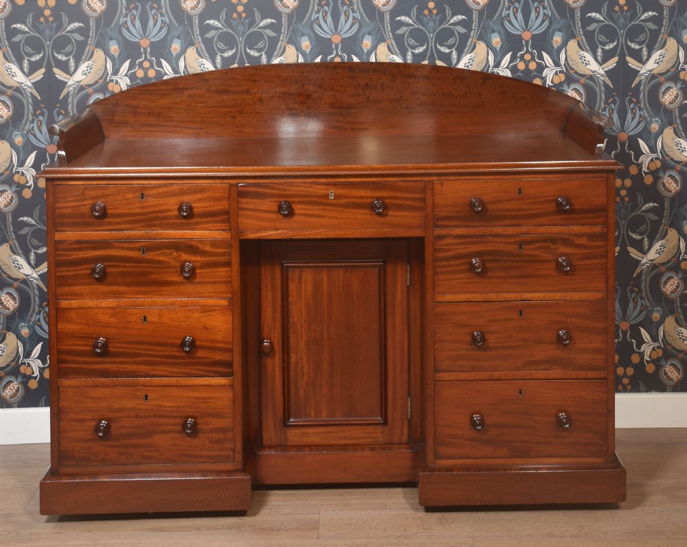A nineteenth-century mahogany kneehole dressing table featuring an arched gallery upstand, nine drawers with turned handles, and a central cupboard door. View II