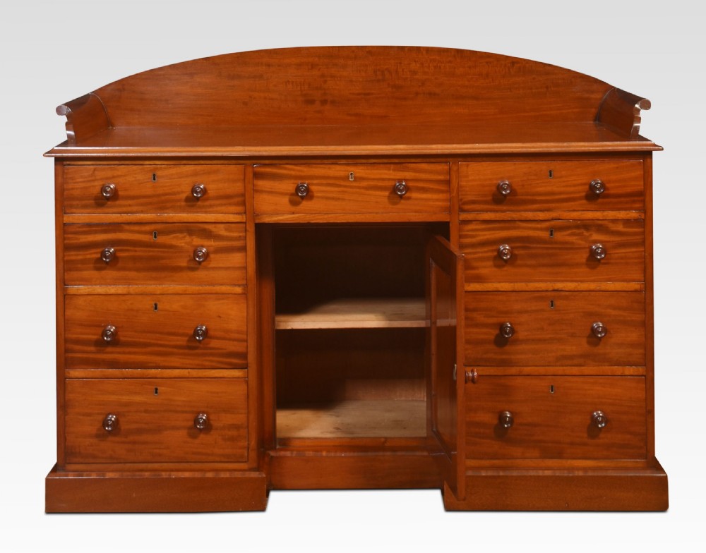A nineteenth-century mahogany kneehole dressing table featuring an arched gallery upstand, nine drawers with turned handles, and a central cupboard door. View III