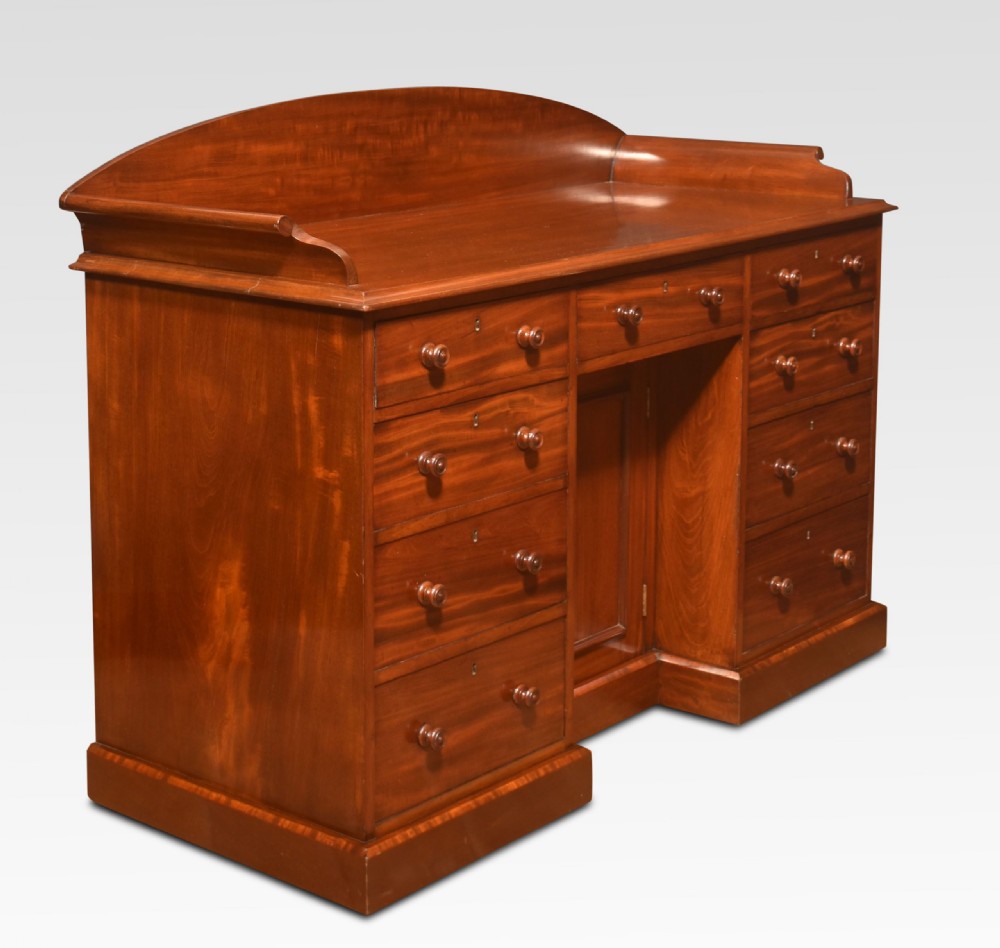 A nineteenth-century mahogany kneehole dressing table featuring an arched gallery upstand, nine drawers with turned handles, and a central cupboard door. View V