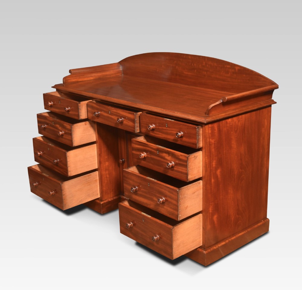 A nineteenth-century mahogany kneehole dressing table featuring an arched gallery upstand, nine drawers with turned handles, and a central cupboard door. View VIII