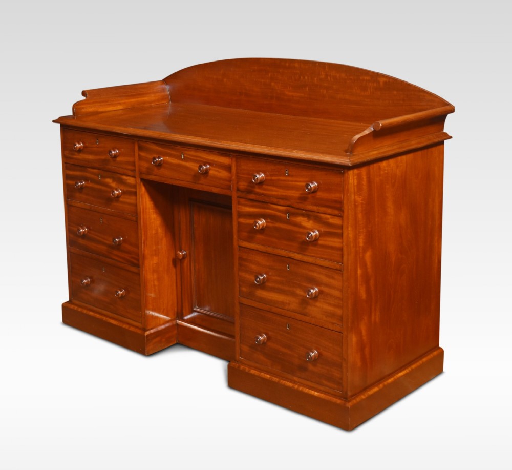 A nineteenth-century mahogany kneehole dressing table featuring an arched gallery upstand, nine drawers with turned handles, and a central cupboard door. View IX