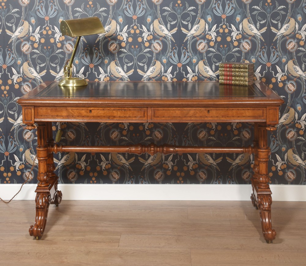 A Victorian walnut writing desk with an inset dark leather surface, frieze drawers, turned side columns, and carved scroll trestle feet. View II