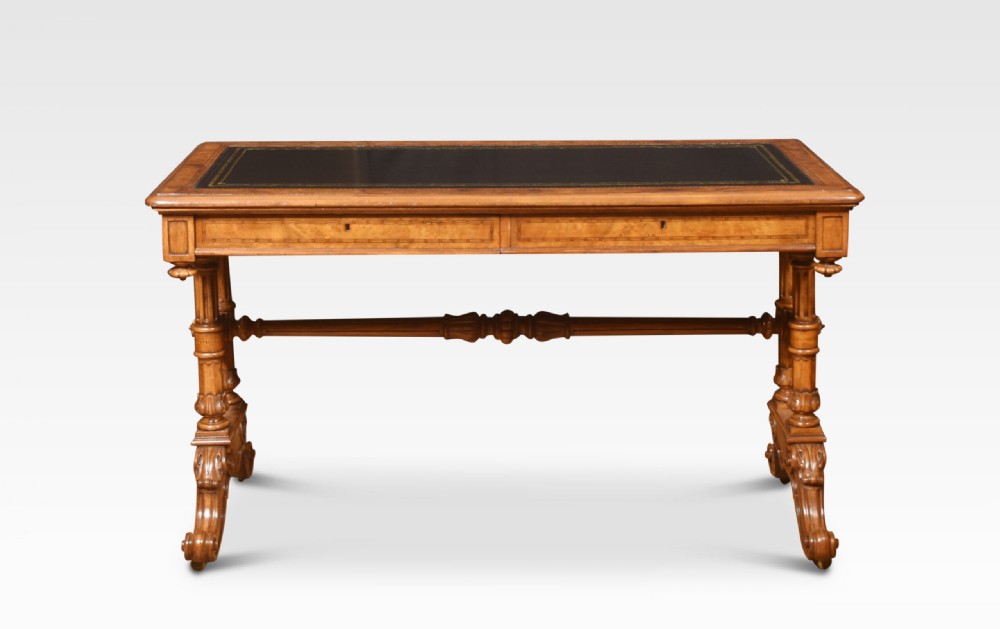A Victorian walnut writing desk with an inset dark leather surface, frieze drawers, turned side columns, and carved scroll trestle feet. View VI
