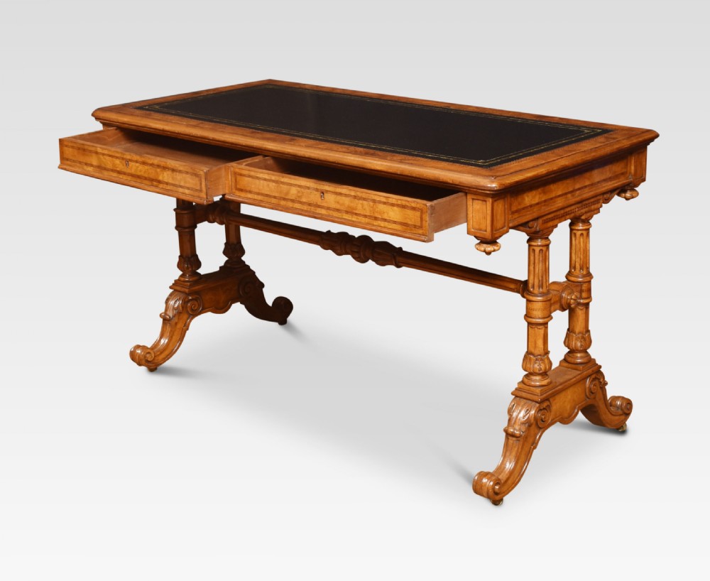A Victorian walnut writing desk with an inset dark leather surface, frieze drawers, turned side columns, and carved scroll trestle feet. View VIII