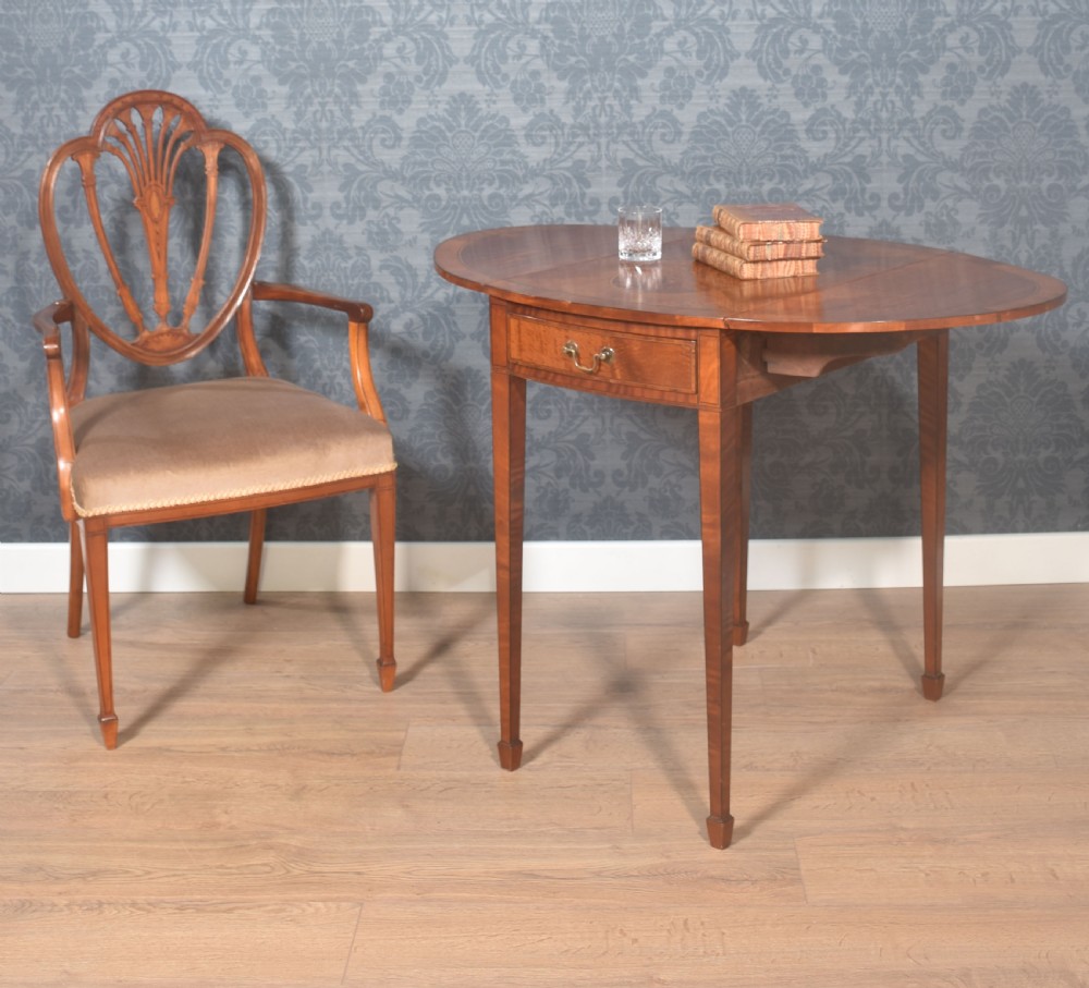A George III style satinwood Pembroke table featuring an oval burr veneer central inlay, drop-leaf sides, a single drawer with a brass handle, and square tapered legs terminating in spade feet. View II