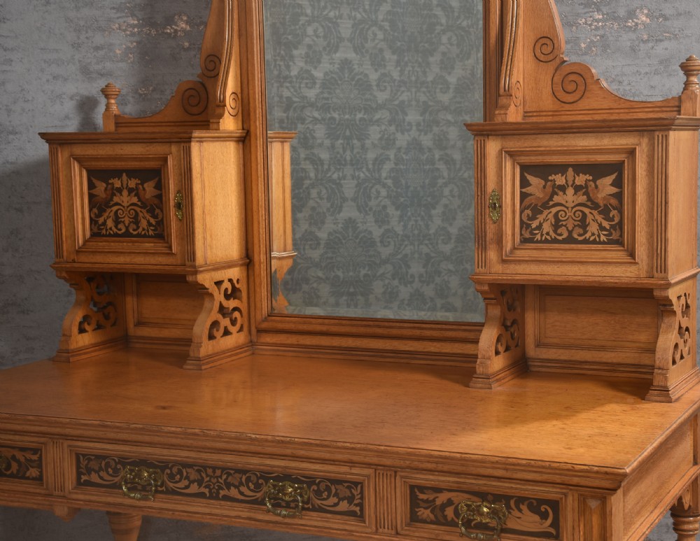 An oak dressing table featuring marquetry inlay patterns on the drawers and side cabinets, a central rectangular mirror, turned legs, and an H-stretcher. View II