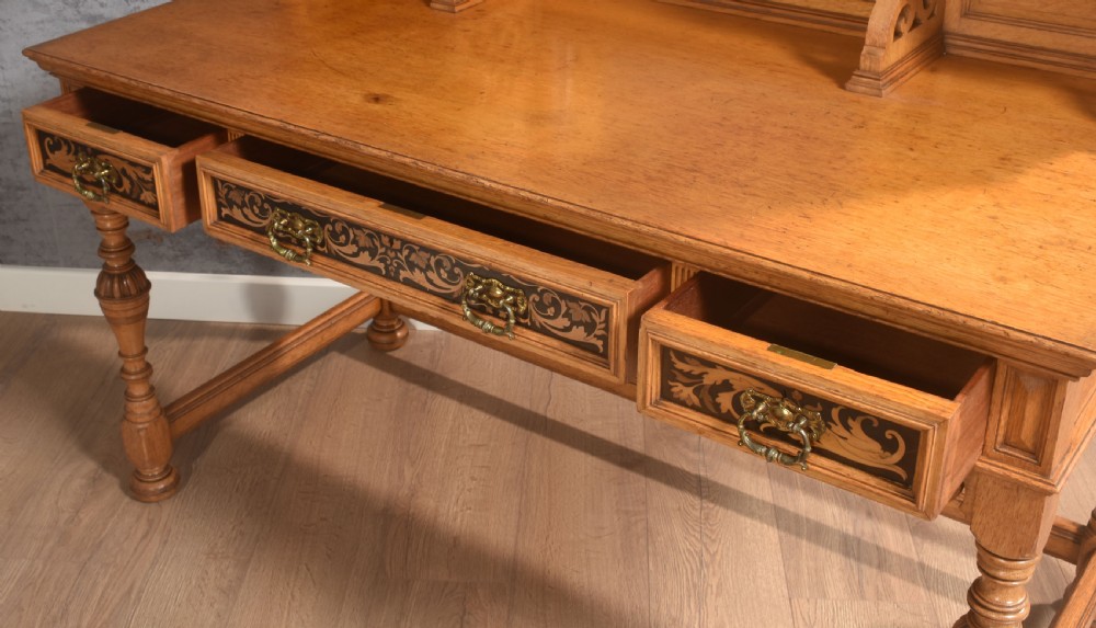 An oak dressing table featuring marquetry inlay patterns on the drawers and side cabinets, a central rectangular mirror, turned legs, and an H-stretcher. View XIII