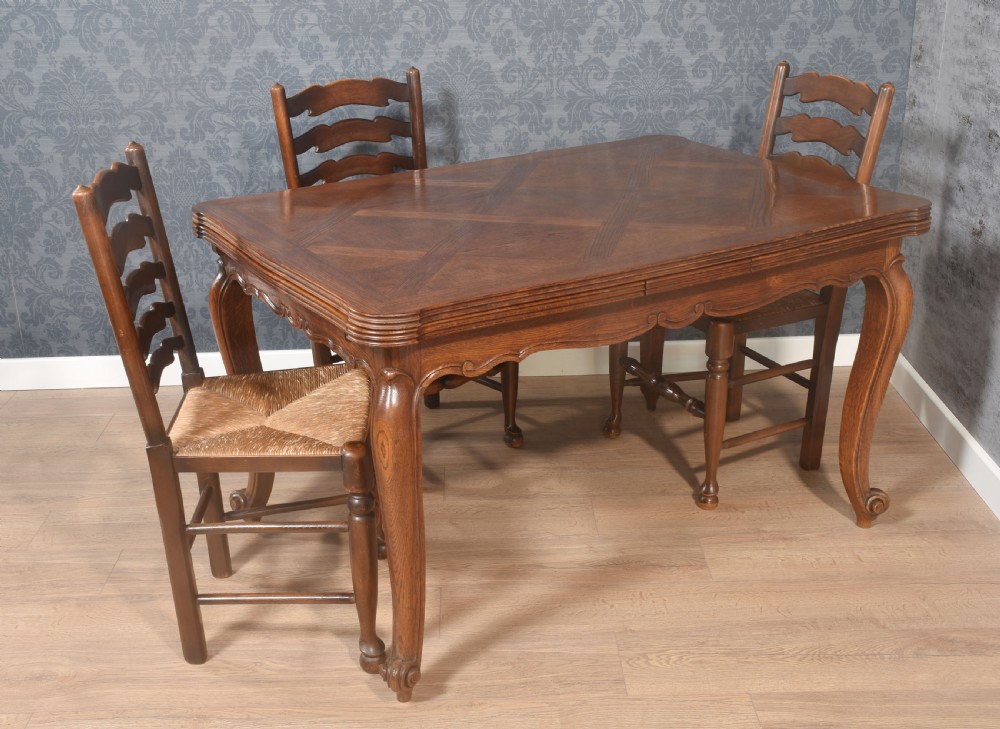 A French oak dining table featuring a geometric parquetry top, shaped apron, cabriole legs, and a draw-leaf extension mechanism. View II
