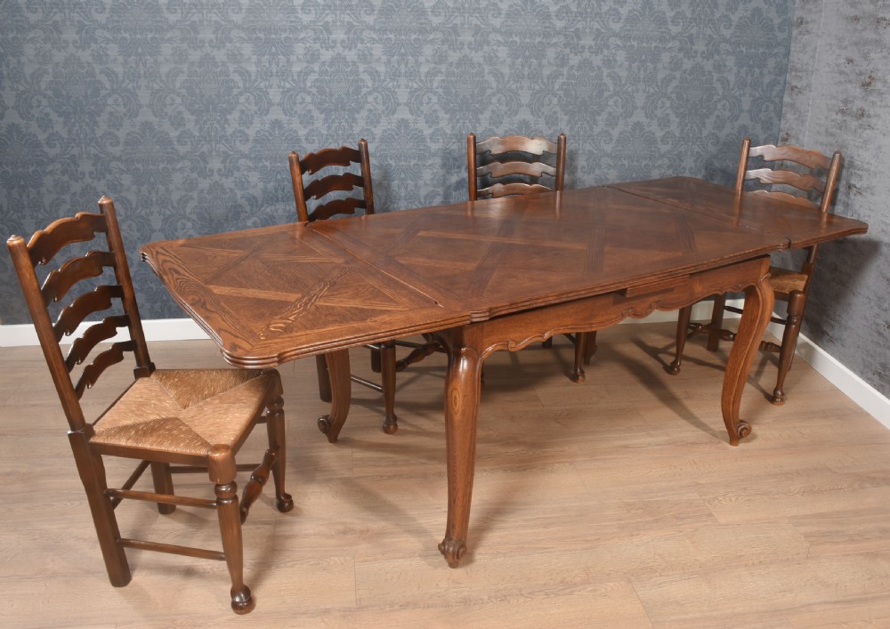 A French oak dining table featuring a geometric parquetry top, shaped apron, cabriole legs, and a draw-leaf extension mechanism. View IV