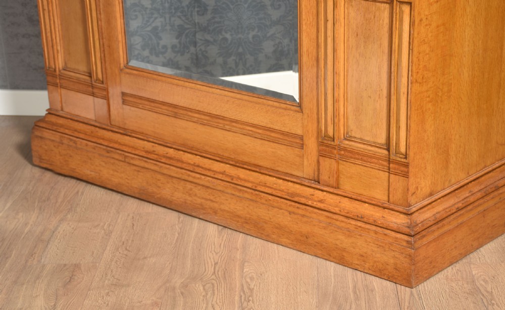 A Victorian golden oak wardrobe featuring a central mirrored door flanked by recessed panels with elaborate marquetry inlay and fluted pilasters. View V