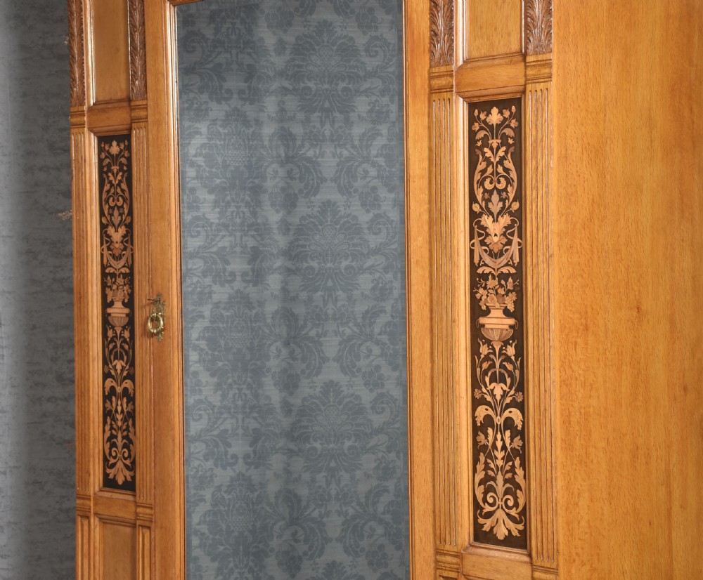 A Victorian golden oak wardrobe featuring a central mirrored door flanked by recessed panels with elaborate marquetry inlay and fluted pilasters. View VII