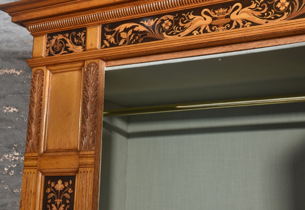 A Victorian golden oak wardrobe featuring a central mirrored door flanked by recessed panels with elaborate marquetry inlay and fluted pilasters. View X