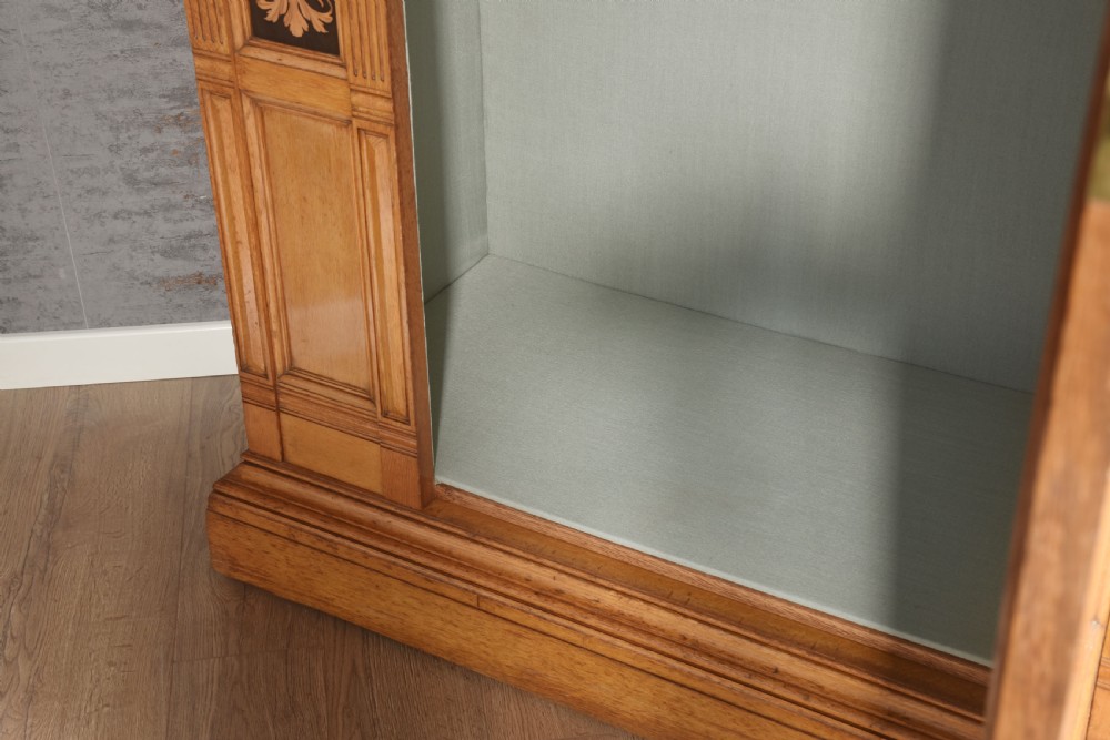 A Victorian golden oak wardrobe featuring a central mirrored door flanked by recessed panels with elaborate marquetry inlay and fluted pilasters. View XI