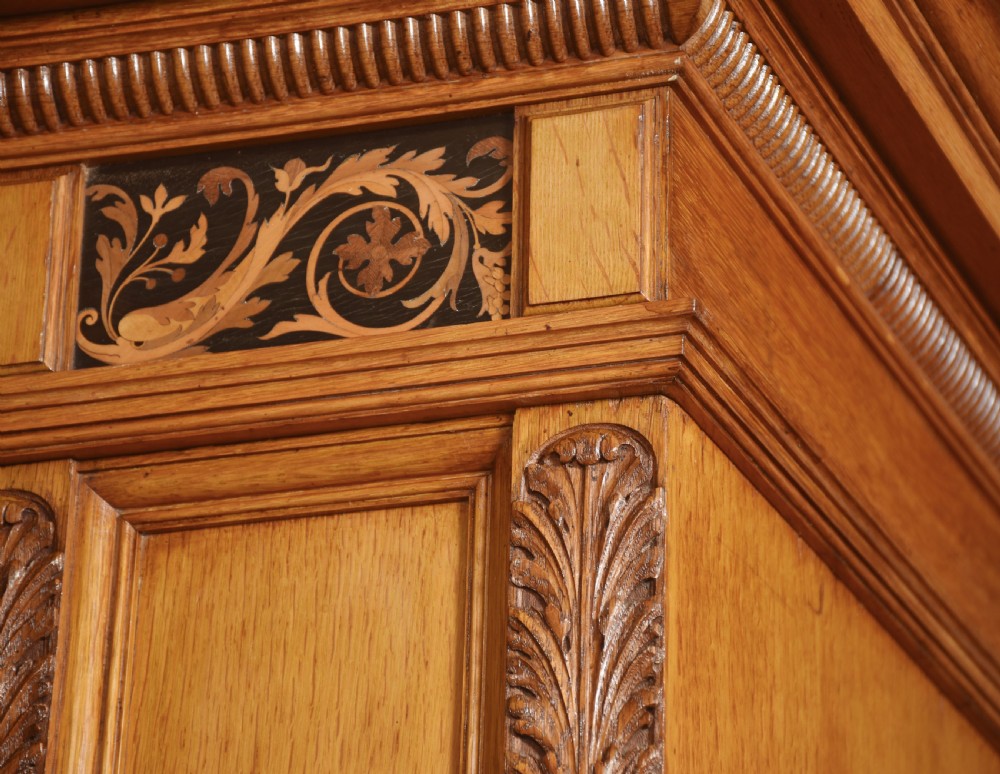 A Victorian golden oak wardrobe featuring a central mirrored door flanked by recessed panels with elaborate marquetry inlay and fluted pilasters. View XIII