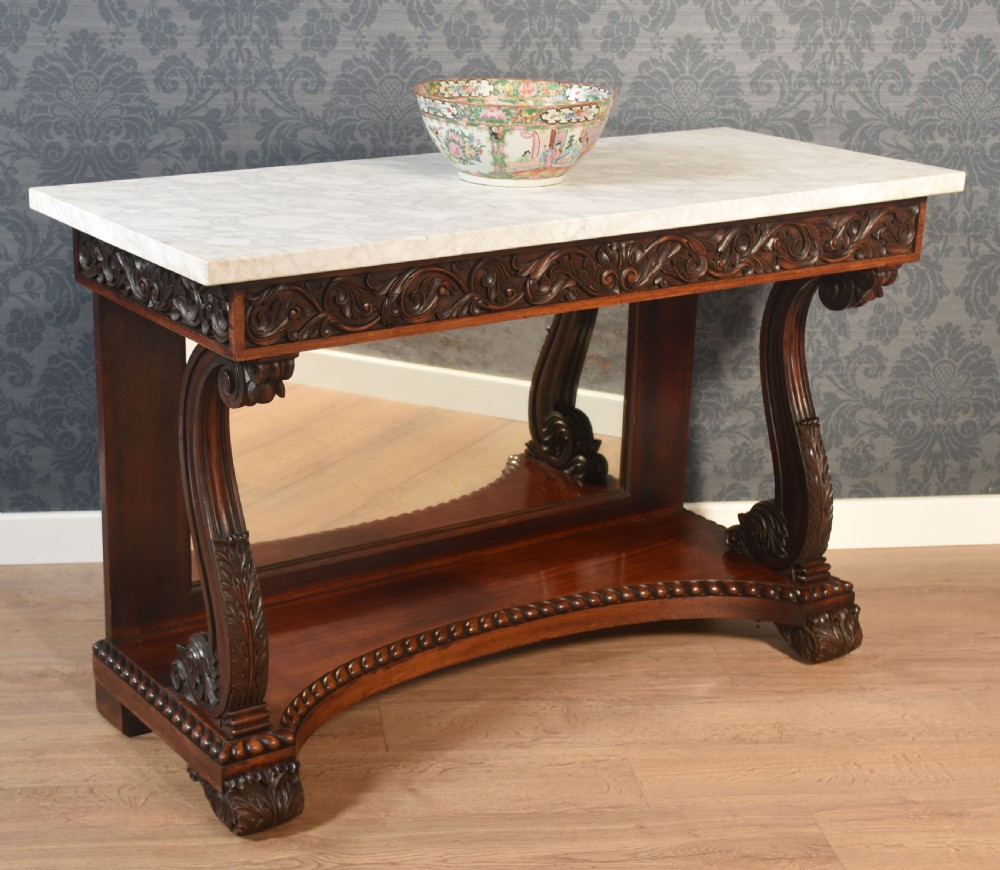 A 19th-century mahogany console table with a rectangular white marble top, carved frieze, S-shaped scroll supports, and an inset mirror back above a shaped plinth base. View V