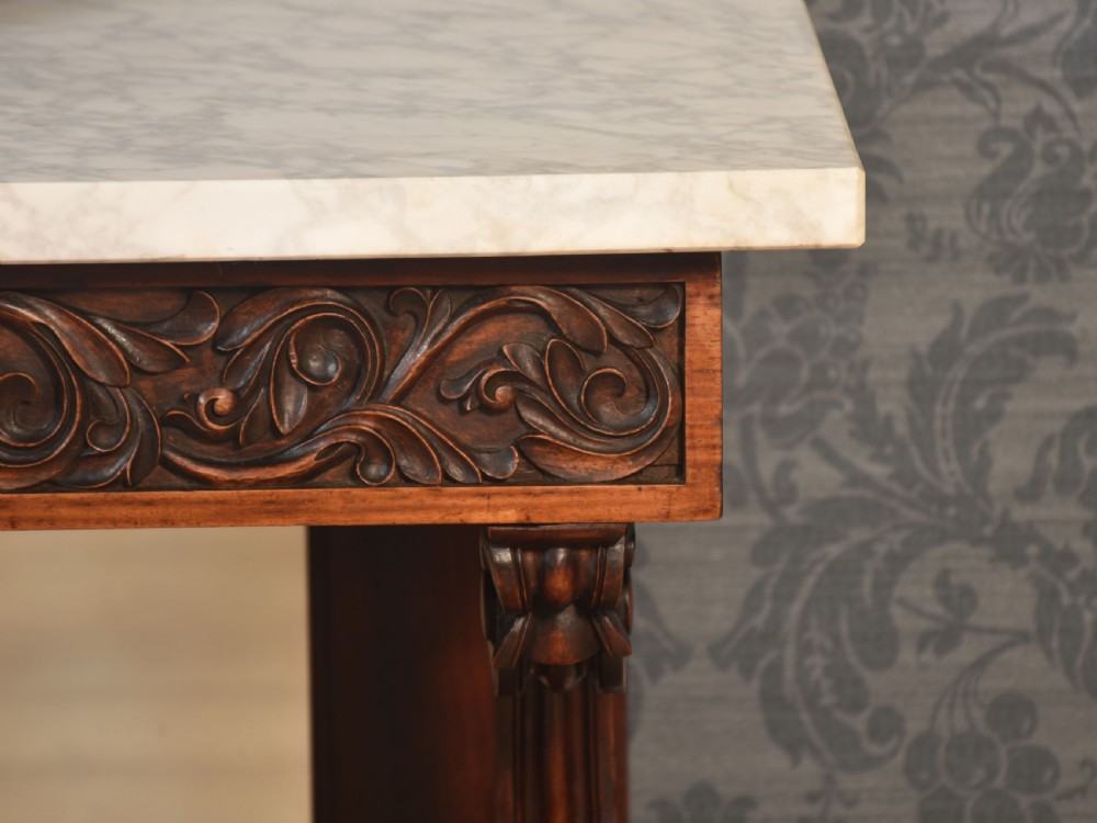 A 19th-century mahogany console table with a rectangular white marble top, carved frieze, S-shaped scroll supports, and an inset mirror back above a shaped plinth base. View VII