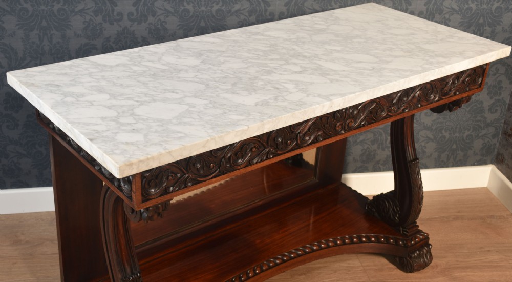 A 19th-century mahogany console table with a rectangular white marble top, carved frieze, S-shaped scroll supports, and an inset mirror back above a shaped plinth base. View IX