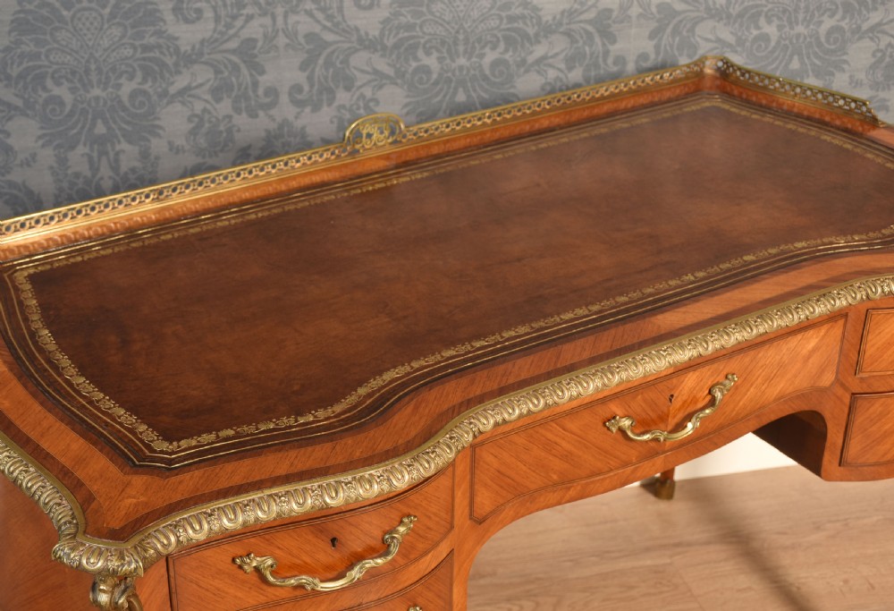 A 19th-century kingwood writing table featuring five drawers, ornate ormolu mounts, cabriole legs, and a leather-inset writing surface. View VI