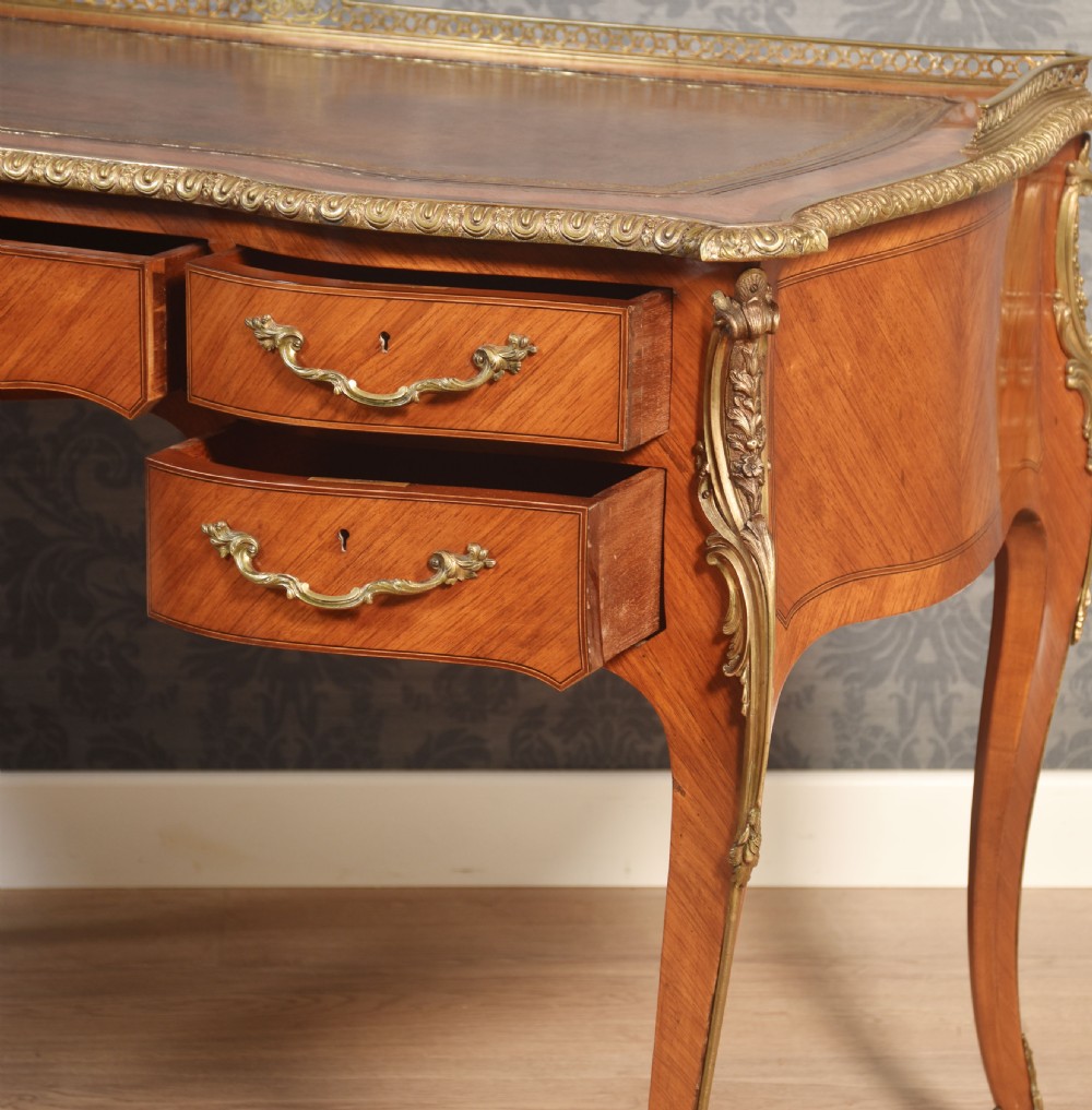 A 19th-century kingwood writing table featuring five drawers, ornate ormolu mounts, cabriole legs, and a leather-inset writing surface. View X