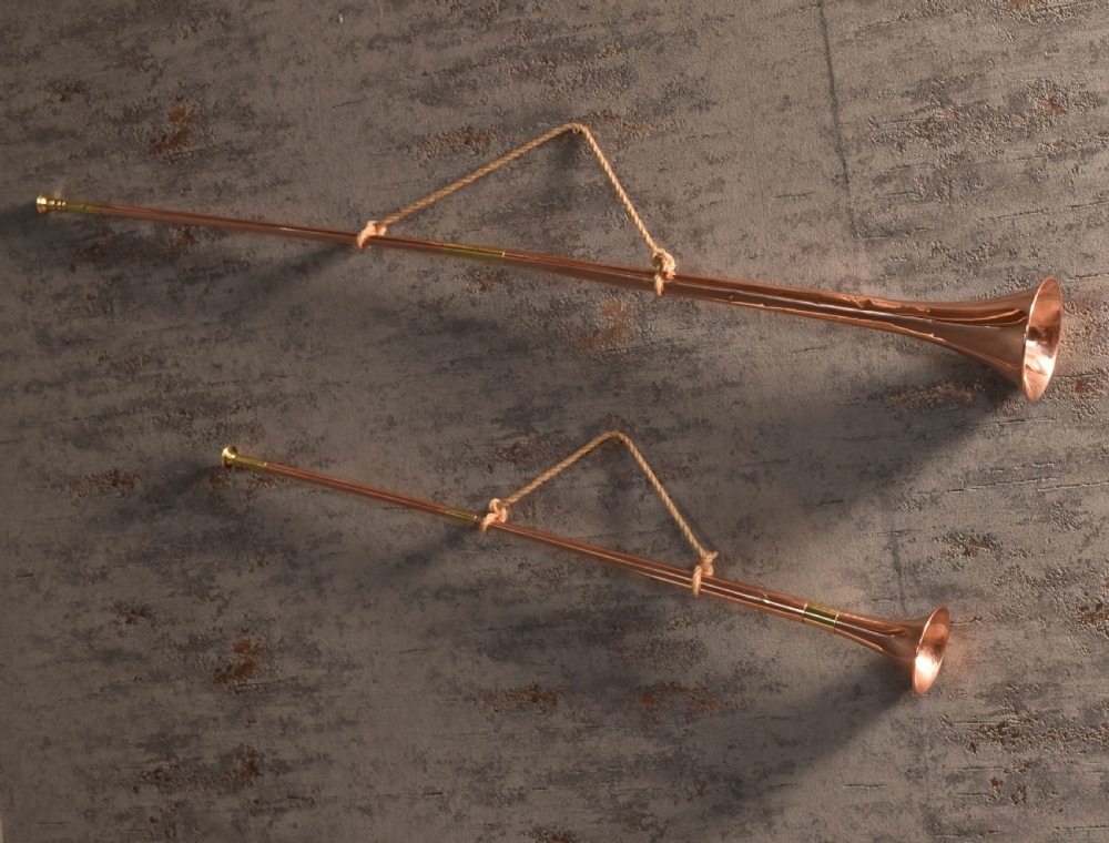 A set of two straight copper coaching horns with brass mouthpieces and flared bells, each rigged with a suspension rope. View IV