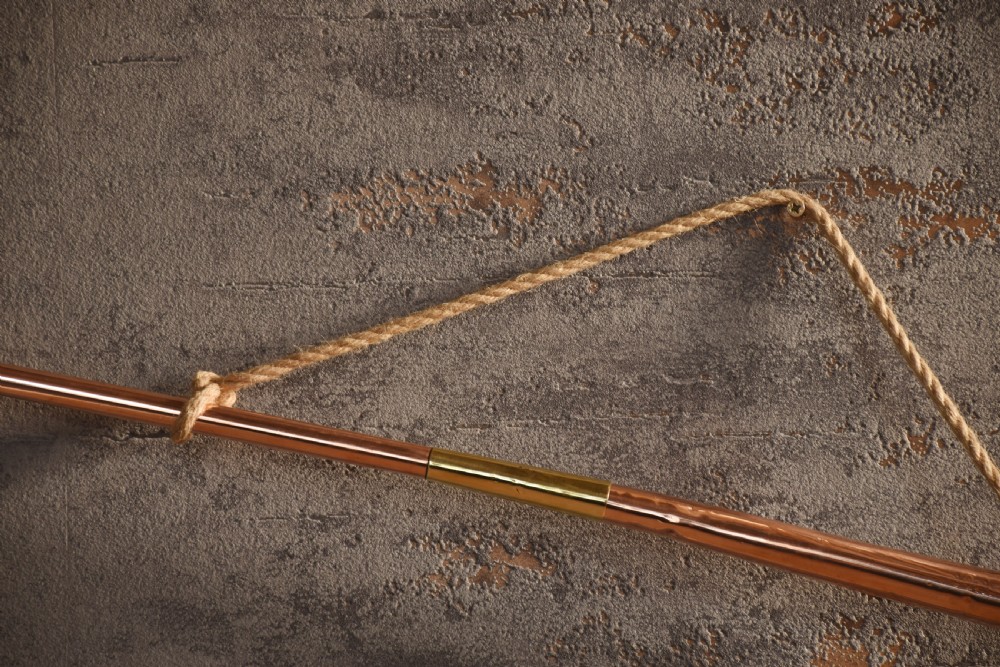 A set of two straight copper coaching horns with brass mouthpieces and flared bells, each rigged with a suspension rope. View VII
