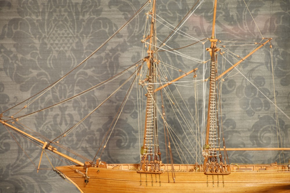 A detailed wooden scale model of a two-masted Scottish schooner with intricate thread rigging, displayed inside a clear glass case with a brass plaque. View VI