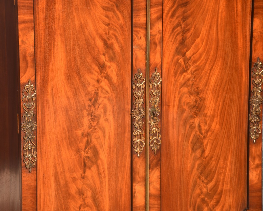 A matching pair of low mahogany side cabinets featuring double panel doors with figured flame grain and decorative gilt metal mounts. View V