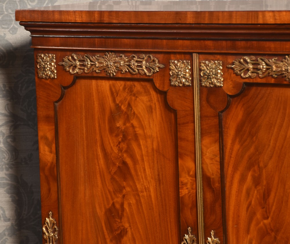 A matching pair of low mahogany side cabinets featuring double panel doors with figured flame grain and decorative gilt metal mounts. View VI