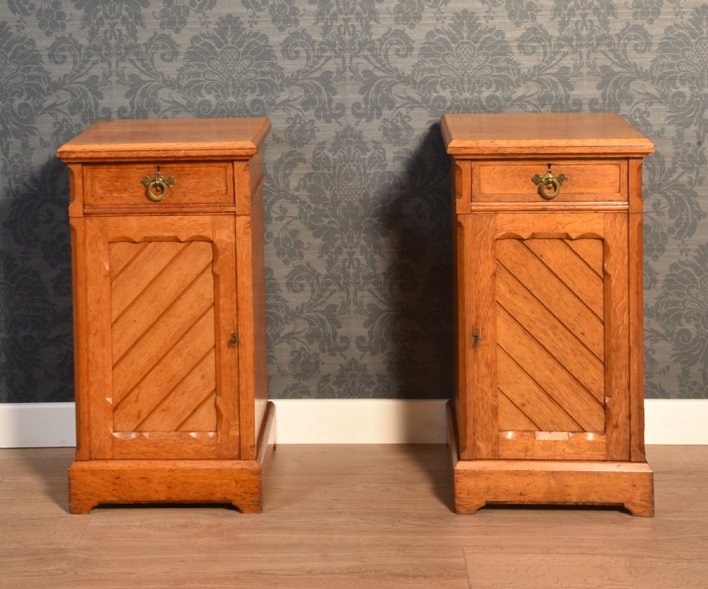 A matching pair of golden oak bedside cabinets featuring single top drawers with brass ring pulls and lower cupboard doors with diagonal plank detailing. View II