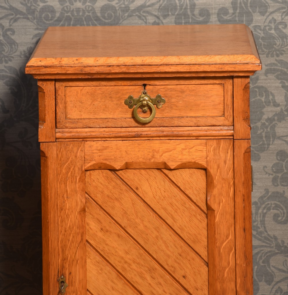 A matching pair of golden oak bedside cabinets featuring single top drawers with brass ring pulls and lower cupboard doors with diagonal plank detailing. View III