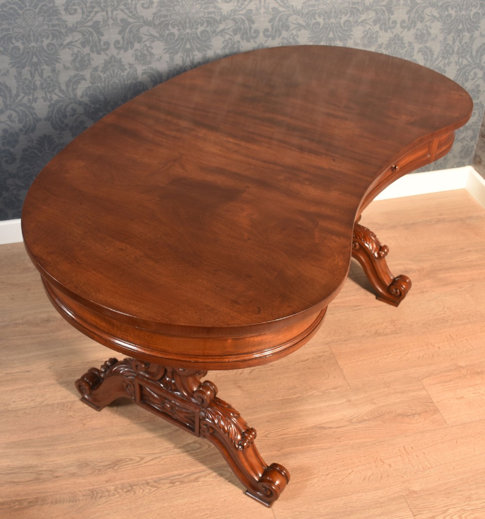 A Victorian mahogany kidney-shaped desk featuring carved trestle legs, a turned stretcher, and a single frieze drawer. View III