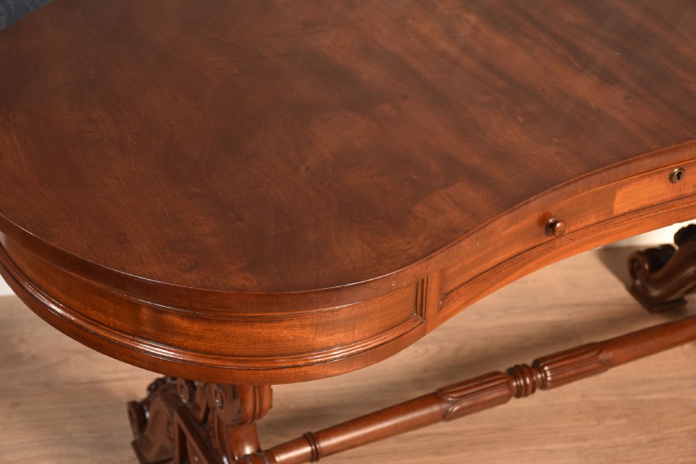 A Victorian mahogany kidney-shaped desk featuring carved trestle legs, a turned stretcher, and a single frieze drawer. View V