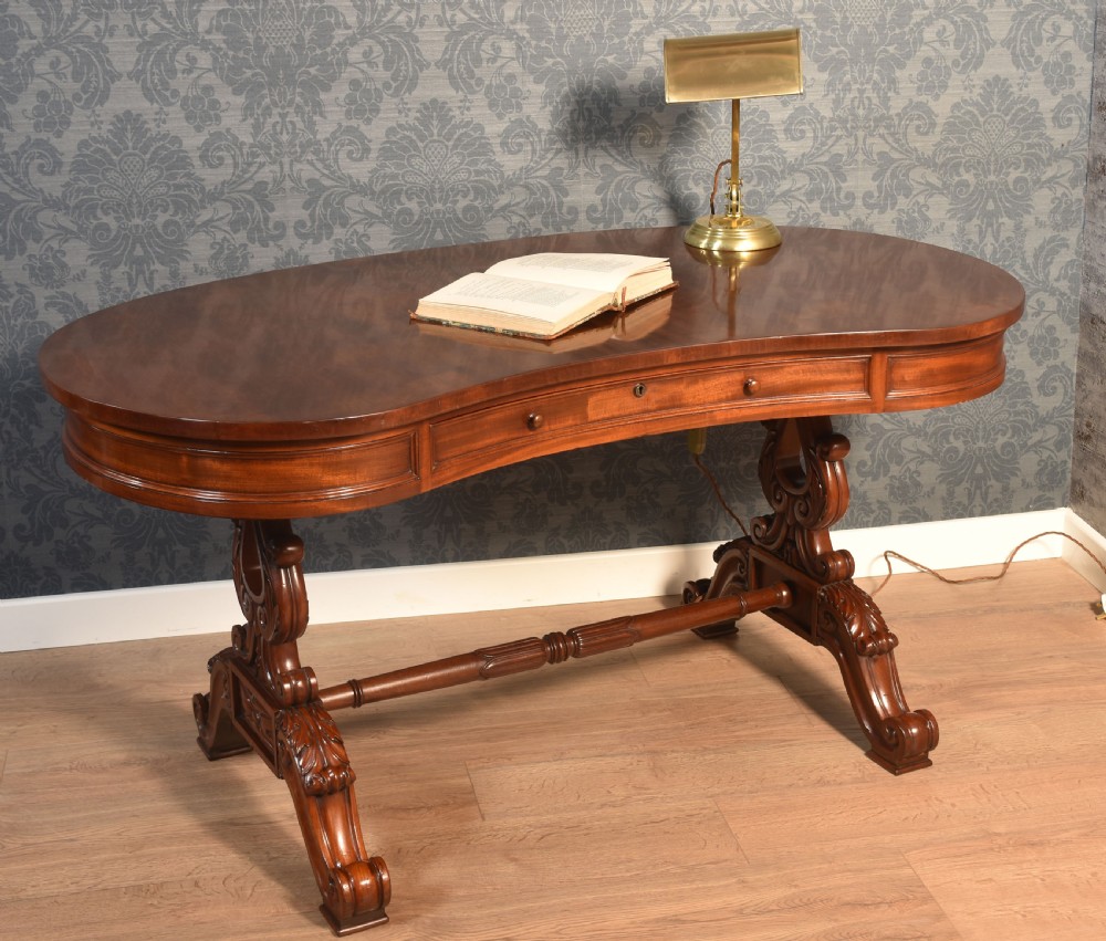 A Victorian mahogany kidney-shaped desk featuring carved trestle legs, a turned stretcher, and a single frieze drawer. View VII