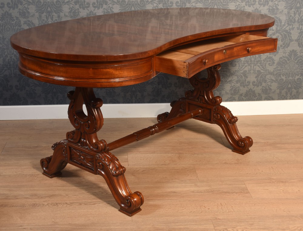 A Victorian mahogany kidney-shaped desk featuring carved trestle legs, a turned stretcher, and a single frieze drawer. View XI